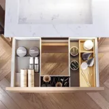 Badeværelse inspiration med vaskeskabe samt overskabe i lys eg med lameller, elegant dobbelt håndvask, smukt spejlskab med lys, sildebensgulv i lys træ og hvid marmorvæg giver et klassisk, lyst og stilrent udtryk.