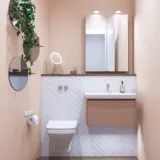 Lille badeværelse inspiration med lille vaskeskab i specialfarve med integreret greb, spejlskab med lamper, dekorationsspejl med tonet glashylde, hvide sildebensfliser på væggen giver et stilrent og klassisk udtryk.