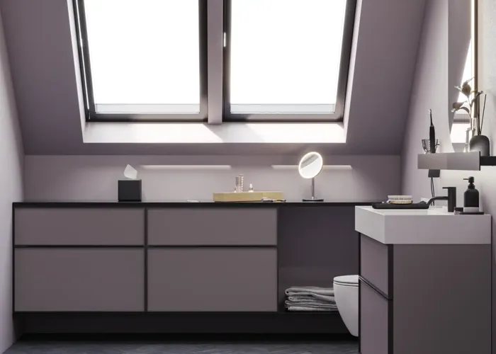 Badeværelse med skrå vægge inspiration, med badeværelsesmøbler i lilla med elegante rammefronter, flot ovalt spejl med lampe, smuk og praktisk hylde, samt lillamalet væg og gråt sildebensgulv, der giver et elegant og moderne udtryk.