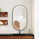 Moderne og stilfuld badeværelse inspiration med oval spejl med sort ramme og lysstyring, farvet toilet, vaskeskab, underskabe og skabe i rødbrun eg, Silestone vask og matchende gulv