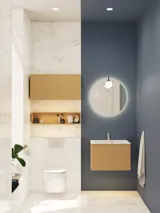 Lille, stilfuldt badeværelse med mørkeblå vægge, bløde gule badeværelsesmøbler med riller, og elegant rundt spejl med lampe