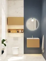 Lille, stilfuldt badeværelse med mørkeblå vægge, bløde gule badeværelsesmøbler med riller, og elegant rundt spejl med lampe