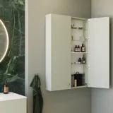 Stilfuldt og luksuriøst badeværelse med blide grønne nuancer, et stort elegant rundt spejl og et moderne, sofistikeret grønt toilet