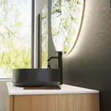 Minimalistisk og stilrent badeværelse inspiration med vaskeskab, underskabe og højskabe i gylden eg, stort rundt spejl med lysstyring, farvet toilet og bordstående håndvask