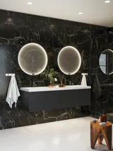 Elegant og moderne badeværelse inspiration med mørke marmorvægge, runde oplyste spejle med sort ramme, væghængt vaskeskab med dobbeltvask og en rummelig bruseniche