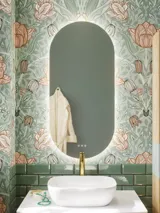 Badeværelse inspiration med grønne møbler i specialfarve med sider i natur eg, elegante riller, stilfuld bordplade med romantisk oval håndvask, smukt ovalt spejl og blomstret tapet giver et yndefuldt, vintage retro udtryk.