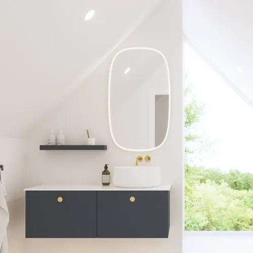 Elegant og moderne badeværelse inspiration med skrå loft, væghængte blå vaskeskab og underskabe, rund vask med messing armatur, oplyst spejl og naturligt lysindfald
