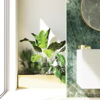 Stilfuldt og luksuriøst badeværelse med blide grønne nuancer, et stort elegant rundt spejl og et moderne, sofistikeret grønt toilet