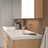Moderne makeup-bord i nordisk stil med lyst træ, elegant belysning, spejl og opbevaringshylder, der skaber en stilfuld og funktionel plads.