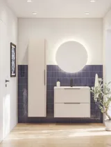 Badeværelse inspiration med aflange blå fliser, elegant beige vaskeskab og højskab med sorte, minimalistiske og aflange greb samt rundt spejl med lys, der giver et smukt og kontrastfyldt udtryk.