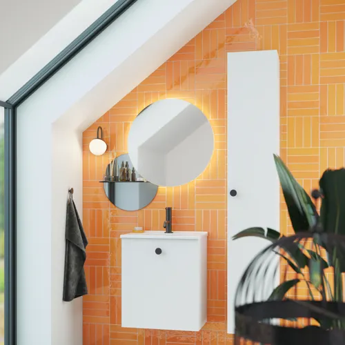 Badeværelse med skrå loft inspiration med lille hvidt vaskeskab samt højskab med runde sorte greb, samt smukt rundt spejl, orange fliser giver et friskt og moderne udtryk.