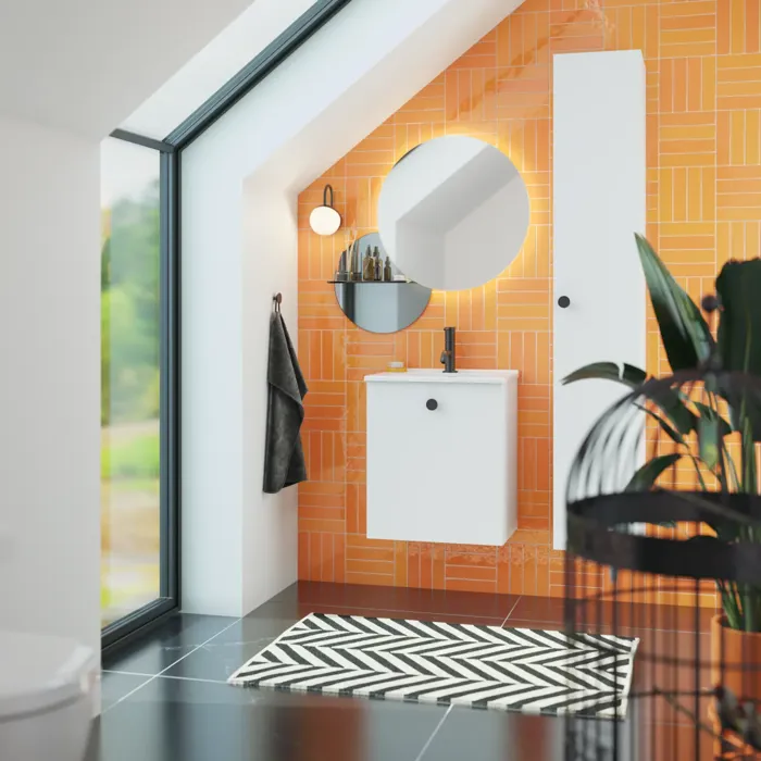 Badeværelse med skrå loft inspiration med lille hvidt vaskeskab samt højskab med runde sorte greb, samt smukt rundt spejl, orange fliser giver et friskt og moderne udtryk.