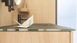 Stilfuldt badeværelse i skandinavisk og japandi indretningsstil med lyse trævægge, rundt spejl og minimalistiske badeværelsesmøbler.