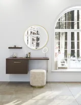 Nordisk stil badeværelse inspiration med vaskeskab og underskabe i røget eg, makeupplads, sidestillet håndvask, rundt messing spejl med ramme og synlige charmerende træbjælker.