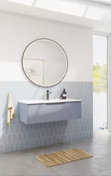 Badeværelse inspiration med aflange lyseblå fliser og betongulv, elegant vaskeskab i lys blå og smukke smalle striber, stilren og tynd håndvask, dobbelt højskab med smukke smalle striber, samt minimalistisk rundt spejl med sort kant og lys.