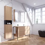Badeværelse inspiration med vaskeskabe samt overskabe i lys eg med lameller, elegant dobbelt håndvask, smukt spejlskab med lys, sildebensgulv i lys træ og hvid marmorvæg giver et klassisk, lyst og stilrent udtryk.