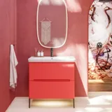 Badeværelse inspiration med røde vægge, blødt formede røde vaskeskabe og højskab, elegant hvid håndvask og smukt ovalt spejl med lys, der sammen med de naturlige omgivelser skaber et vintage udtryk