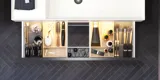 Badeværelse med skrå vægge inspiration, med badeværelsesmøbler i lilla med elegante rammefronter, flot ovalt spejl med lampe, smuk og praktisk hylde, samt lillamalet væg og gråt sildebensgulv, der giver et elegant og moderne udtryk.